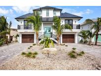 Two-story home with a metal roof, two-car garage, and landscaped front yard at 243 S Harbor Dr, Holmes Beach, FL 34217