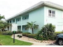 Quaint two-story condo building exterior with lush landscaping and walkways at 611 Gulf N Dr # D24, Bradenton Beach, FL 34217