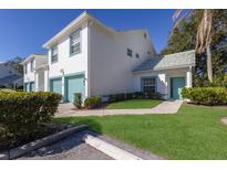 Two-story condo with teal accents, attached garage, and landscaped lawn at 6591 Fairway Gardens Dr # 2-102, Bradenton, FL 34203