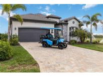 Luxury home with paver driveway, golf cart, and lush landscaping at 5757 Cheech Gln, Bradenton, FL 34211