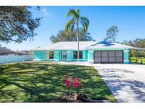 Charming light teal house with metal roof, palm tree, and landscaped yard at 1814 E Leewynn Dr, Sarasota, FL 34240