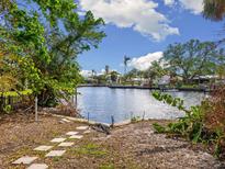 Peaceful canal-front view with lush landscaping and a glimpse of neighboring homes at 4865 Featherbed Ln, Sarasota, FL 34242