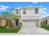 Two-story house with a white exterior, two-car garage, and landscaping at 17014 Wave Tressle Pl, Wimauma, FL 33598