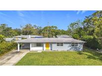 A charming ranch-style home with a yellow door and well-maintained lawn at 2877 Michigan St, Sarasota, FL 34237