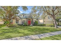 Beautiful one-story home with a red door, lush landscaping, and a large green lawn at 9506 Royal Calcutta Pl, Lakewood Ranch, FL 34202