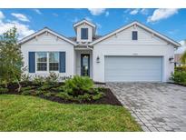 White house with blue shutters, landscaped yard, and paver driveway at 10180 Canaveral Cir, Sarasota, FL 34241
