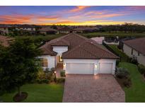 Two-story house with a brick driveway and a three-car garage, at sunset at 13627 American Prairie Pl, Lakewood Ranch, FL 34211