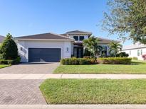 Beautiful single-story home featuring lush landscaping, a paver driveway, and a well-manicured lawn at 5058 Surfside Cir, Lakewood Ranch, FL 34211