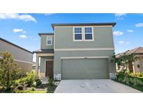 Two-story house with green exterior, two-car garage, and landscaping at 10448 Ladybug Cv, Parrish, FL 34219