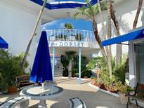 The Dorset building entrance with seating area, lush landscaping, and a blue umbrella at 475 Benjamin Franklin Dr # 209, Sarasota, FL 34236