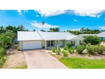 Single-story house with a metal roof, driveway, and landscaped yard at 678 Key Royale Dr, Holmes Beach, FL 34217