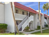 White building with red roof, stairs, and palm trees at 1801 Gulf N Dr # 222, Bradenton Beach, FL 34217