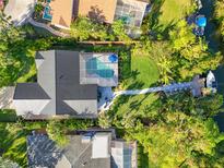 Aerial view of a home with a pool and private dock, showcasing lush landscaping and waterfront access at 1899 Buccaneer Cir, Sarasota, FL 34231