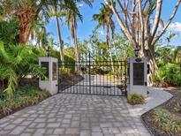 Paved driveway leading to a gated entrance lined with tropical landscaping at 3460 Flamingo Ave, Sarasota, FL 34242