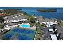 Aerial view showcases a community with tennis courts, pool, and bay access, all nestled in a serene waterfront setting at 4234 Gulf Of Mexico Dr # Y2, Longboat Key, FL 34228