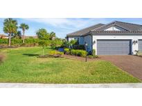 Charming single-story home featuring a well-manicured lawn, lush landscaping, and a brick-paved driveway leading to a two-car garage at 4705 Tortona Ct, Bradenton, FL 34211