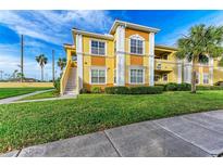 Building exterior showcasing a yellow two-story building with landscaping and walkway at 1195 Villagio Cir # 201, Sarasota, FL 34237