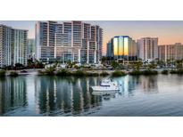 Aerial view of waterfront property with boat and city skyline at sunset at 1155 N Gulfstream Ave # 908, Sarasota, FL 34236