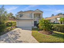 Two-story house with a light gray exterior, a brick driveway, and palm trees at 11216 Coralbean Dr, Lakewood Ranch, FL 34202