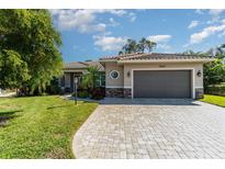 Single-story home with a tile roof, paver driveway, and landscaped lawn at 5868 Meriwether Pl, Sarasota, FL 34232