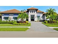 Luxury home with a brick driveway, landscaping, and palm trees at 9224 Starry Night Ave, Sarasota, FL 34241