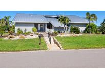 Gray house with metal roof, landscaping, and paved pathway at 120 Lookout Point Dr, Osprey, FL 34229