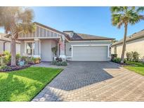 Gray Craftsman style home with a brick paver driveway and lush landscaping at 14924 Sora Way, Bradenton, FL 34212