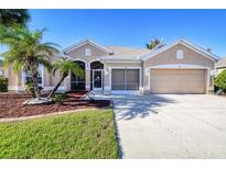 Tan house with palm trees, landscaped yard, and a three-car garage at 5352 Layton Dr, Venice, FL 34293