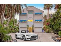 Stunning three-story white home with a two-car garage, blue awnings, and beautiful landscaping at 681 Casey Key Rd, Nokomis, FL 34275