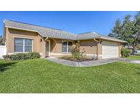 Tan house with gray roof, attached garage, and well-maintained lawn at 2004 14Th Street W Ct, Palmetto, FL 34221