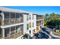 Two-story building with screened balconies overlooking a parking area at 3601 E Bay Dr # 203, Holmes Beach, FL 34217