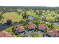 Aerial view of villas with tile roofs near a golf course and waterway at 7320 Golf Pointe Cir, Sarasota, FL 34243