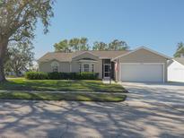 Tan one-story house with a white garage door and well-manicured lawn at 6405 61St E Dr, Palmetto, FL 34221