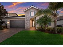 Beautiful single-Gathering home featuring a stone facade, a well-manicured lawn, and mature palm trees at 12232 Perennial Pl, Lakewood Ranch, FL 34211