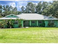 Single story home featuring a large front yard, colorful landscaping, and a well maintained green lawn at 1496 Palm View Rd, Sarasota, FL 34240