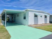 White single-wide mobile home with carport and light green driveway at 11200 Walsingham Rd # 66, Largo, FL 33778