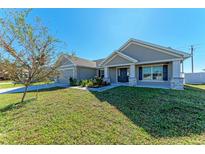 One-story home with gray siding, a dark gray door, and a landscaped lawn at 3030 58Th E Way, Palmetto, FL 34221