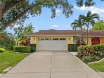 Bright yellow house with red door, attached garage, and landscaped yard at 4662 Long Lake Dr, Sarasota, FL 34233