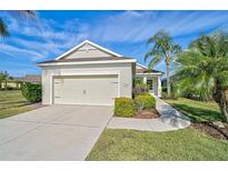 Tan house with two car garage, landscaping, and walkway at 12180 Longview Lake Cir, Bradenton, FL 34211