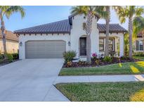 White one-story house with brown roof, landscaping, and a two-car garage at 249 Palmaria Ct, Nokomis, FL 34275