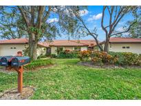 Tan house with brown tile roof, lush landscaping, and a two-car garage at 4577 Pine Green Trl # 2, Sarasota, FL 34241