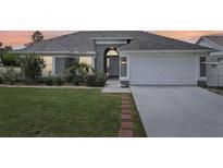 Gray house with white garage door, landscaping, and brick walkway at 716 46Th E St, Bradenton, FL 34208