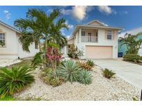 Charming two-story home featuring a balcony and lush tropical landscaping at 109 Tortuga Dr, Nokomis, FL 34275