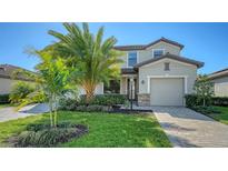 Two-story house with a large palm tree, landscaped lawn, and paver driveway at 17923 Polo Trl, Bradenton, FL 34211