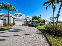 A charming house with a paved driveway, lush landscaping, and palm trees at 3444 Mistletoe Ln, Longboat Key, FL 34228