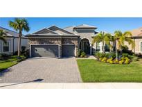 Two-story house with stone accents, three-car garage, and landscaped lawn at 7845 Mainsail Ln, Sarasota, FL 34240