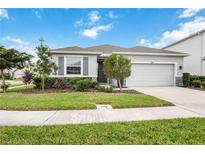 Single-story home with gray exterior, two-car garage, and well-manicured lawn at 12689 Promenade Estates Blvd, Sarasota, FL 34238
