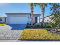 Single-story home with gray exterior, paver driveway, and landscaping at 148 Whiteland Bnd, Nokomis, FL 34275