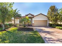 Single-story home with a tan exterior, brown roof, and landscaped lawn at 6870 Willowshire Way, Bradenton, FL 34212
