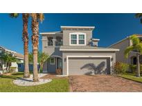 Two-story house with gray siding, brick driveway, and palm trees at 8430 Nandina Dr, Sarasota, FL 34240